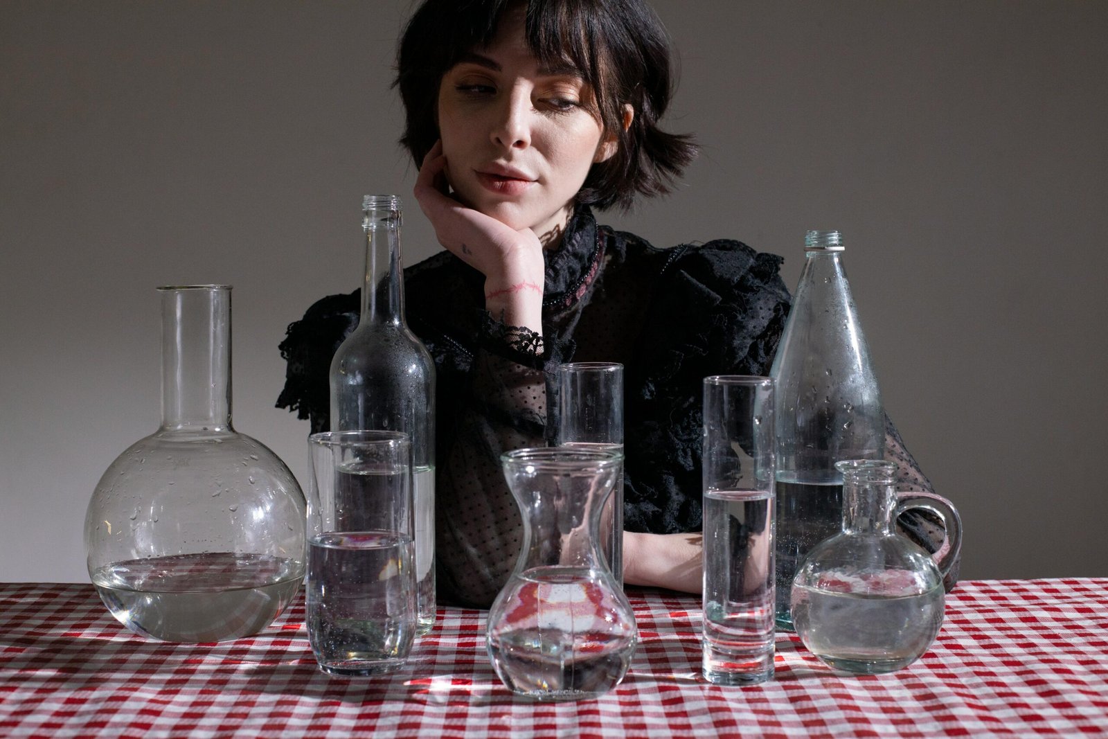 A woman sits at a table surrounded by empty bottles, promoting the importance of hydration with a portable cup.